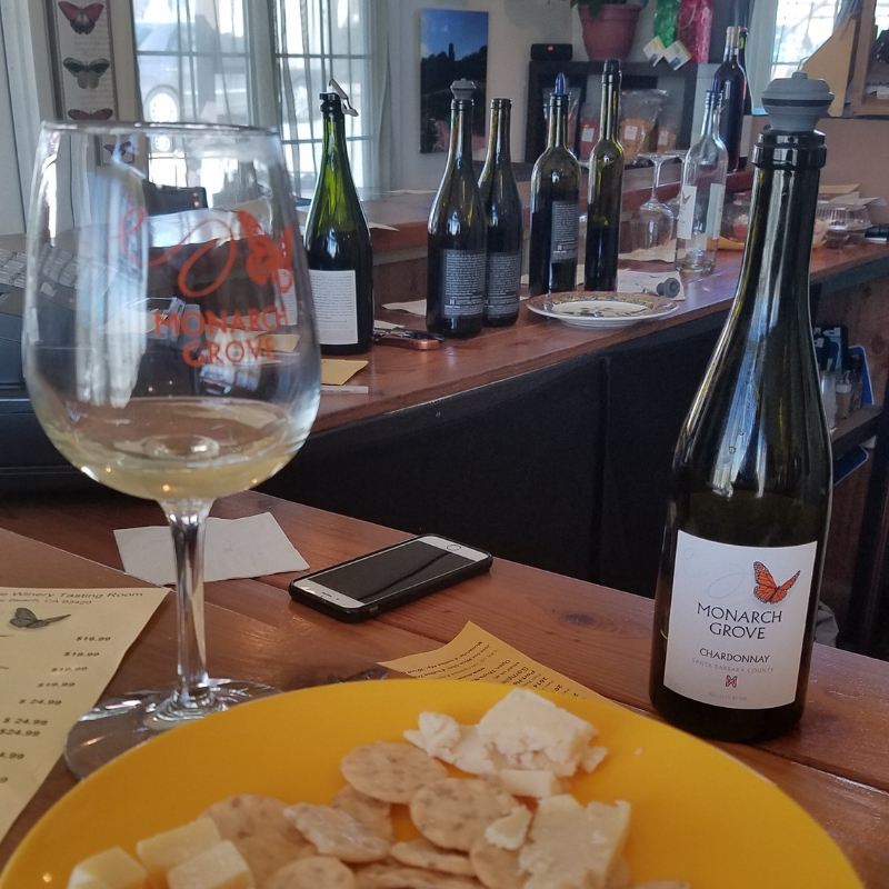 A plate of cheese and crackers alongside a glass of Chardonnay at Monarch Grove Winery